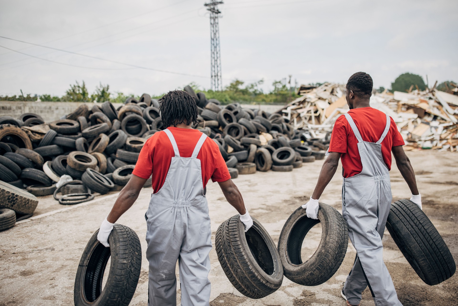 Two workers sorting rubber wheels at the recycling center
